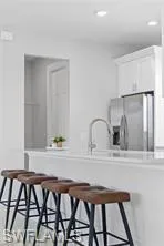 Kitchen with a kitchen breakfast bar, white cabinets, and stainless steel refrigerator with ice dispenser