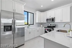 Kitchen featuring stainless steel appliances, white cabinets, and sink
