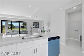 Kitchen with sink, white cabinets, stainless steel dishwasher, and light tile floors