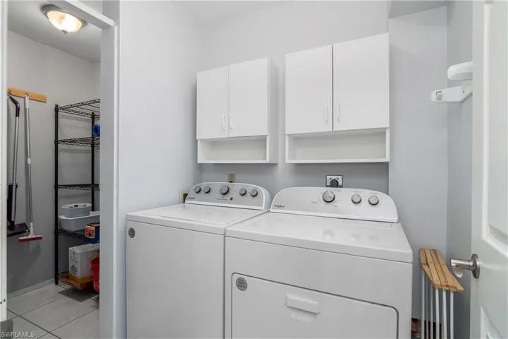 In-residence laundry room with additional storage closet and cabinetry.