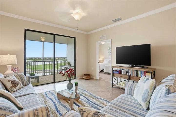 Living area featuring light tile patterned flooring, crown molding, and a ceiling fan