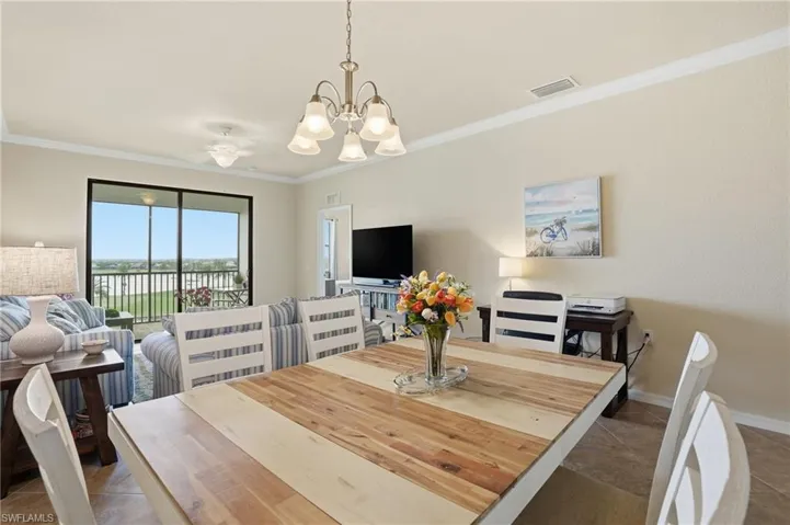 Dining space featuring crown molding, dark tile patterned floors, and a chandelier