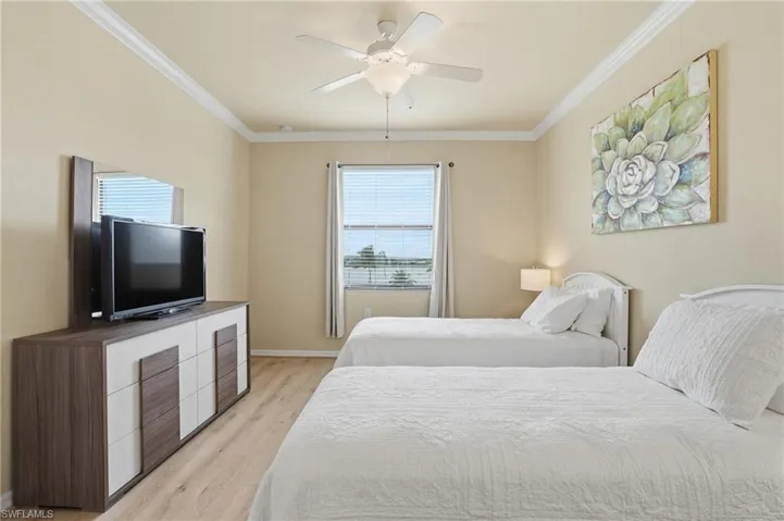 Bedroom with light wood finished floors, ornamental molding, and a ceiling fan