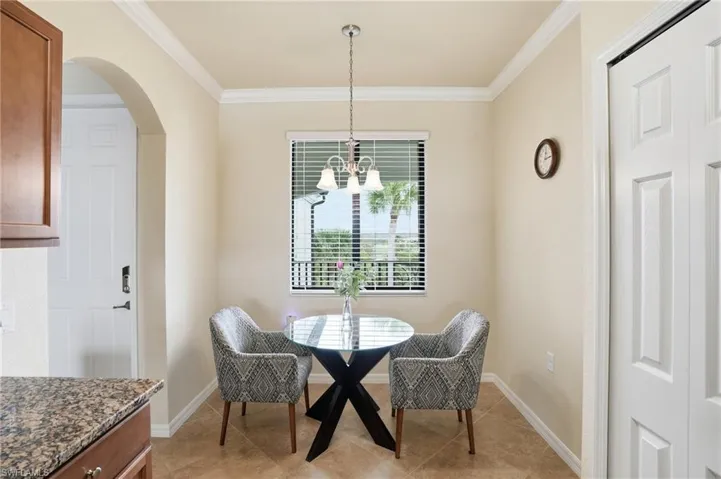 Dining area featuring arched walkways, ornamental molding, a chandelier, and light tile patterned floors