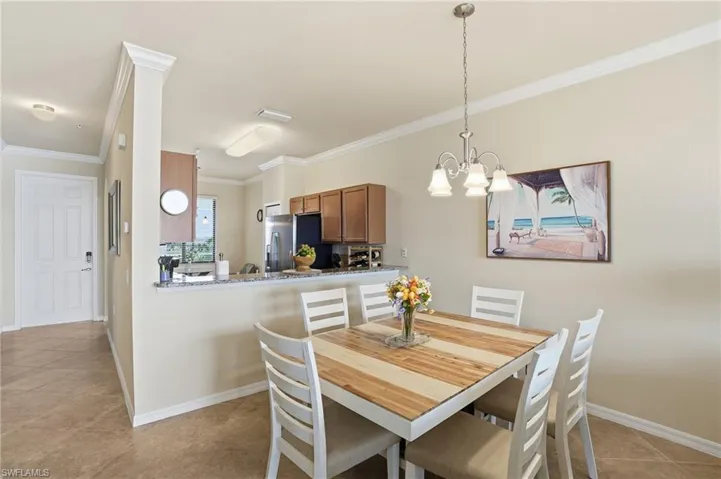 Dining room with light tile patterned flooring, crown molding, and a chandelier