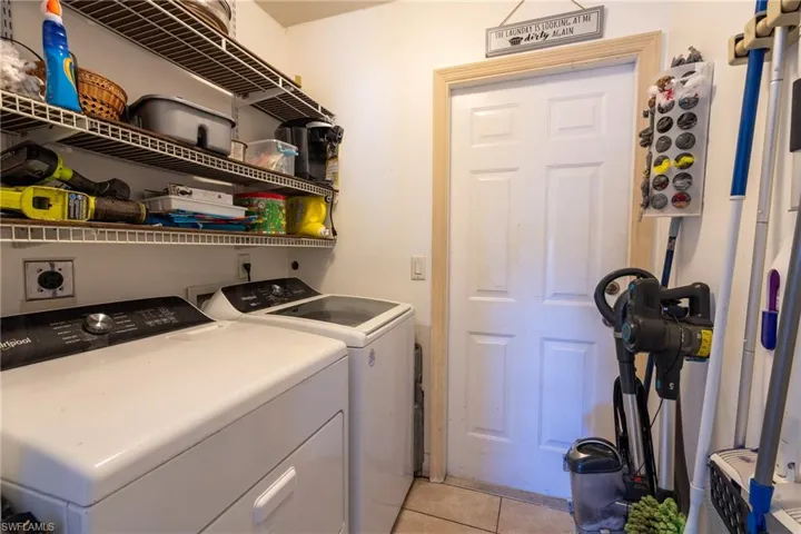 Laundry area featuring laundry area, light tile patterned floors, and washing machine and clothes dryer