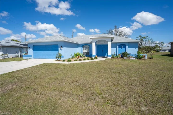 Ranch-style home featuring driveway, stucco siding, a garage, and a front yard
