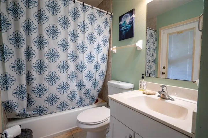 Full bath with shower / bathtub combination with curtain, vanity, toilet, and tile patterned floors