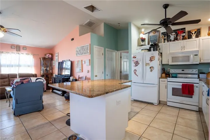 Kitchen with white appliances, visible vents, white cabinets, ceiling fan, and open floor plan