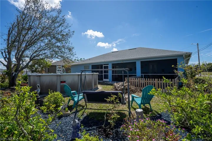 Back of house featuring an outdoor pool, a sunroom, fence, and a shingled roof