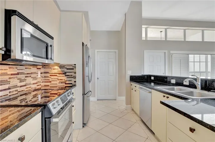Kitchen featuring appliances with stainless steel finishes, tasteful backsplash, a wealth of natural light, and sink