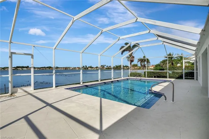 View of swimming pool with a water view, a patio area, and a lanai