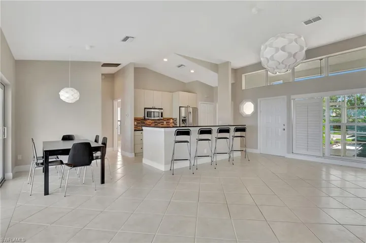 Kitchen with a kitchen bar, white cabinets, light tile patterned flooring, and appliances with stainless steel finishes
