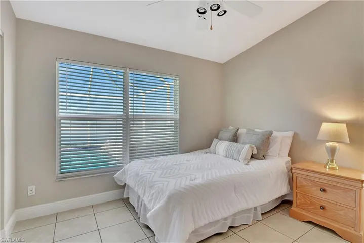 Tiled bedroom with ceiling fan and lofted ceiling