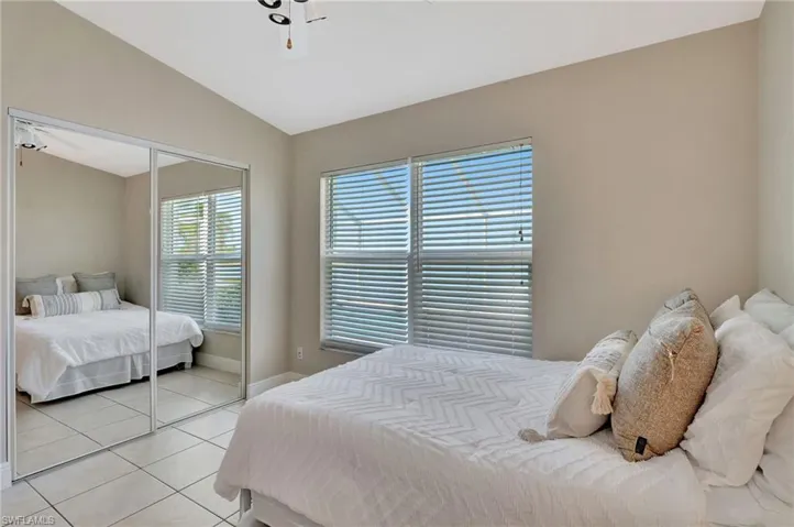 Tiled bedroom with vaulted ceiling and a closet