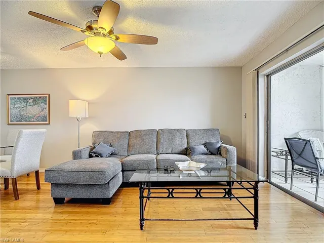 Living room with ceiling fan, a textured ceiling, and light hardwood / wood-style floors