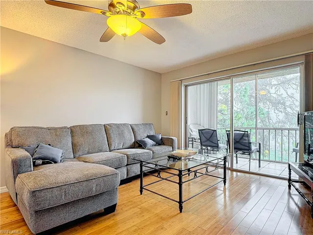 Living room featuring hardwood / wood-style floors, a textured ceiling, and ceiling fan