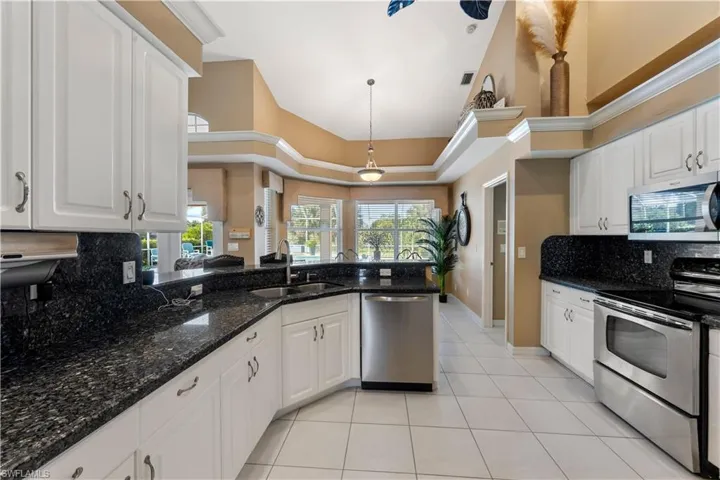 Kitchen with stainless steel appliances, tasteful backsplash, sink, and a high ceiling