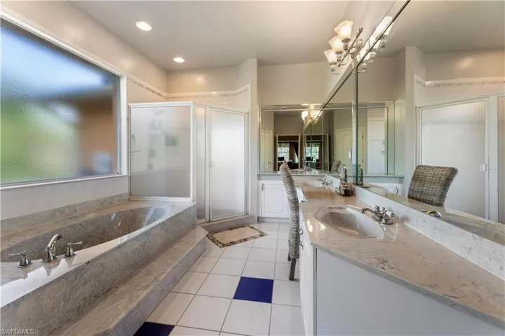 Bathroom with shower with separate bathtub, a chandelier, tile patterned flooring, and double sink vanity