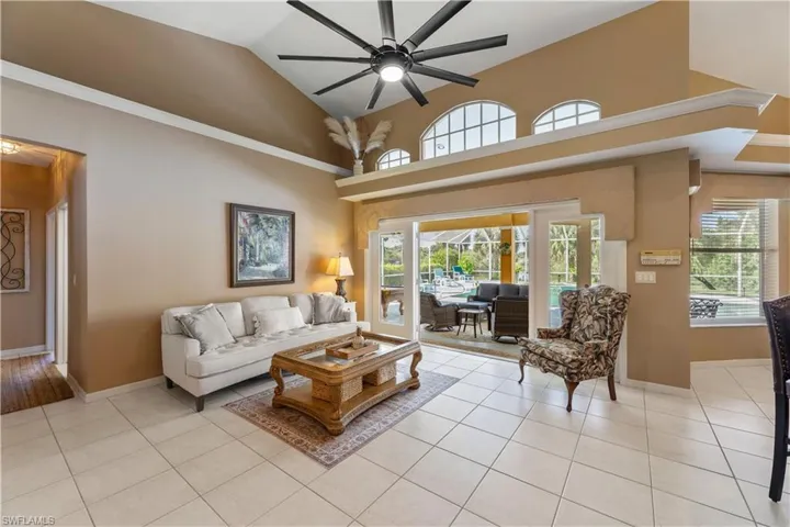 Tiled living room featuring high vaulted ceiling and ceiling fan