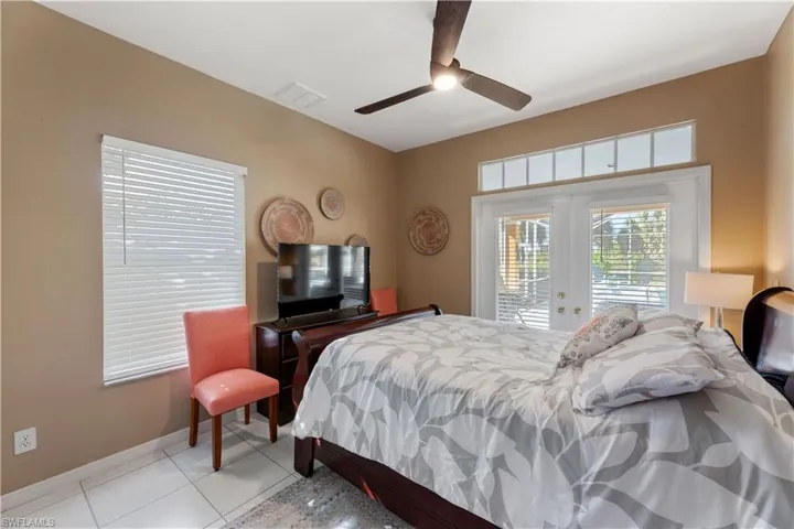 Bedroom featuring french doors, access to exterior, light tile patterned floors, and ceiling fan