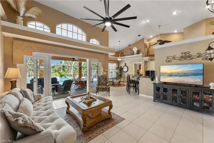 Tiled living room with french doors, high vaulted ceiling, and ceiling fan