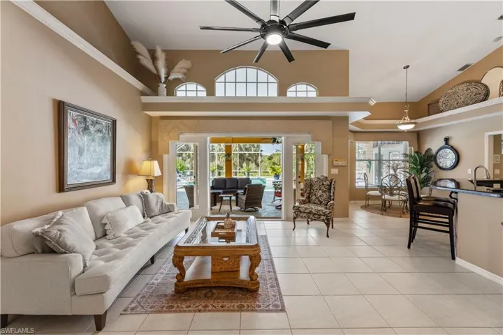 Tiled living room with ceiling fan, sink, and high vaulted ceiling