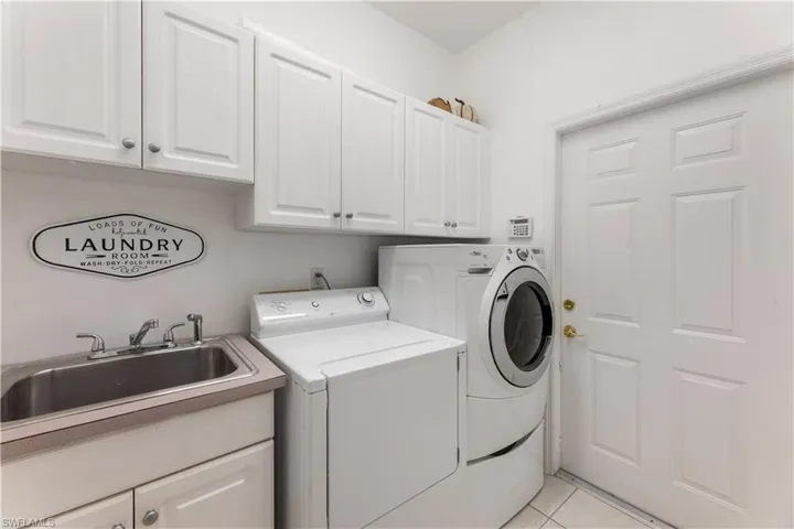 Laundry area with sink, separate washer and dryer, cabinets, and light tile patterned floors