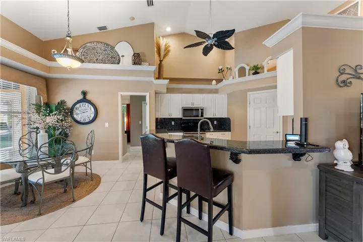 Kitchen with white cabinetry, decorative backsplash, high vaulted ceiling, appliances with stainless steel finishes, and kitchen peninsula