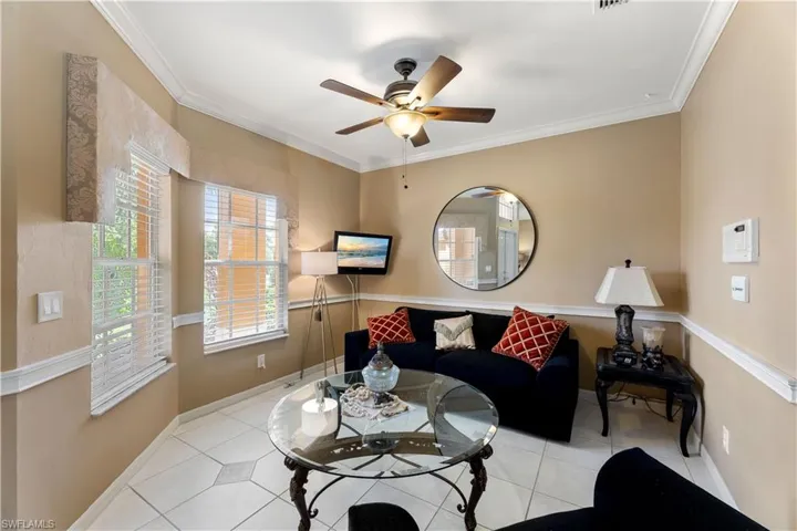 Living room with ornamental molding, light tile patterned floors, and ceiling fan