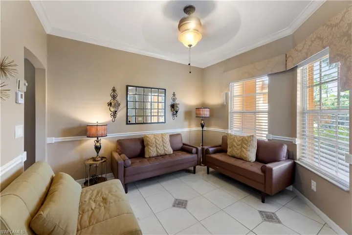Tiled living room with crown molding and ceiling fan