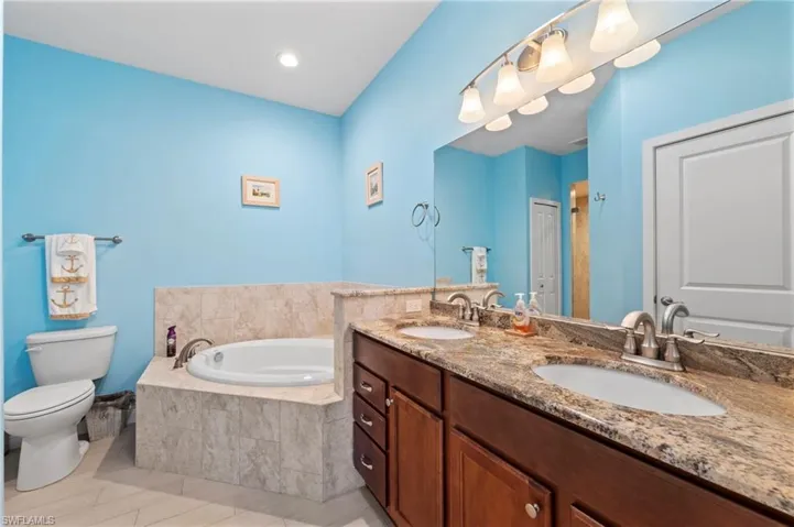 Full bath featuring a bath, double vanity, and light tile patterned flooring