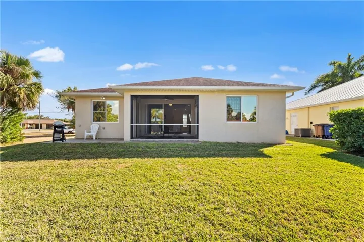 Rear view of property featuring a yard, stucco siding, a patio area, and a ceiling fan
