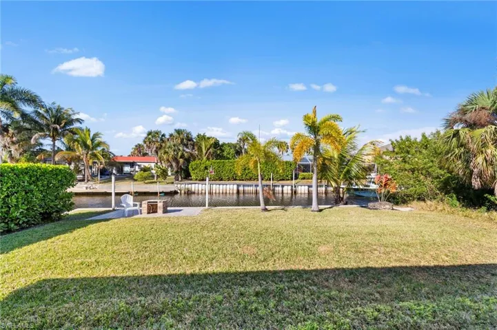 View of green lawn featuring a water view, a patio, and a boat dock
