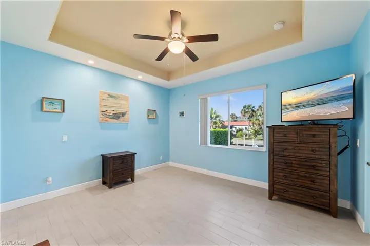 Unfurnished room featuring a ceiling fan, light wood-type flooring, a tray ceiling, and recessed lighting
