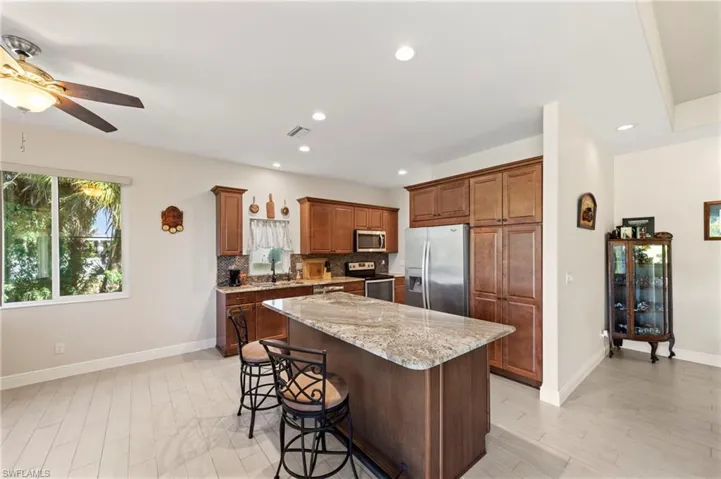 Kitchen with light stone countertops, stainless steel appliances, a breakfast bar, a kitchen island, and decorative backsplash