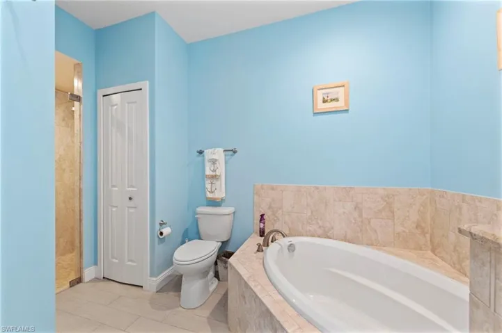 Bathroom featuring a shower stall, a garden tub, tile patterned flooring, and a closet