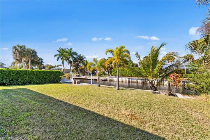View of grassy yard featuring a water view and a boat dock