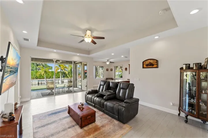 Living room featuring a raised ceiling, light wood-style floors, recessed lighting, and ceiling fan
