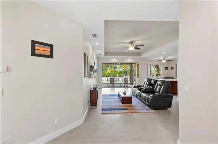 Living area with a raised ceiling, recessed lighting, and ceiling fan