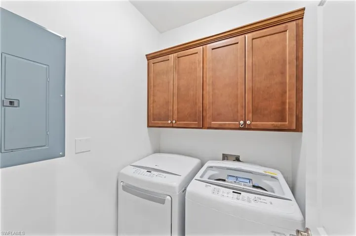 Laundry room featuring electric panel, cabinet space, and washer and clothes dryer