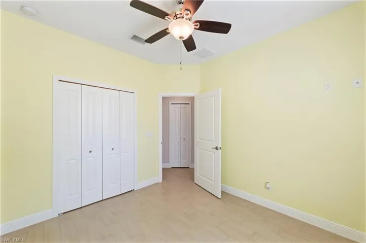 Unfurnished bedroom with light wood-style floors, ceiling fan, and a closet