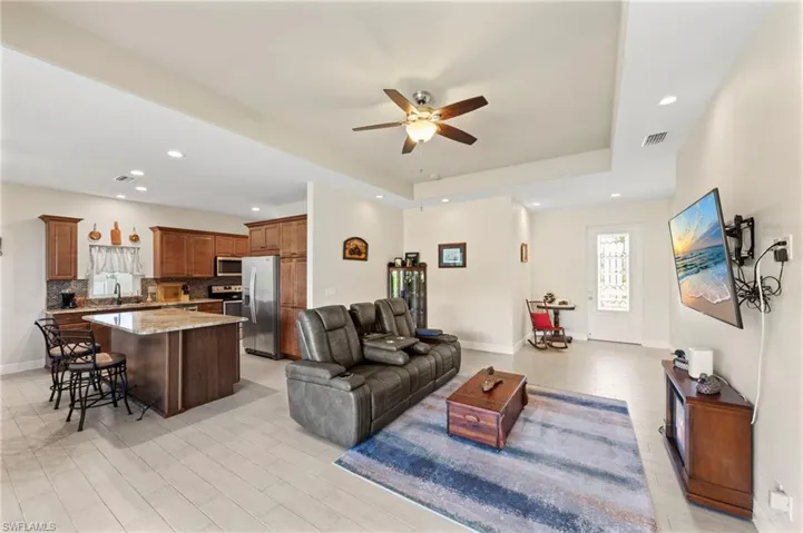 Living room featuring ceiling fan, light wood-style floors, a raised ceiling, and recessed lighting