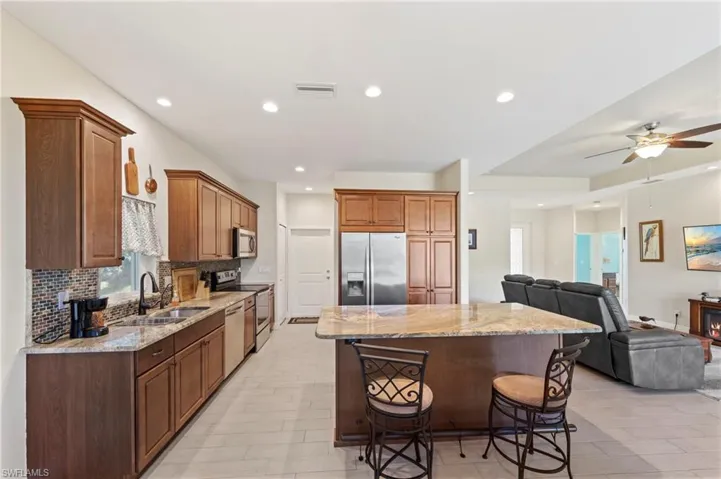 Kitchen with light stone counters, open floor plan, a breakfast bar area, stainless steel appliances, and recessed lighting