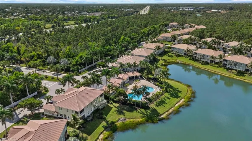 Aerial perspective showcasing a residential community with multiple buildings, a central water feature, and extensive green landscaping