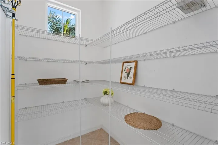 Walk-in pantry with wire shelving, a rectangular window, and neutral-toned floor tile
