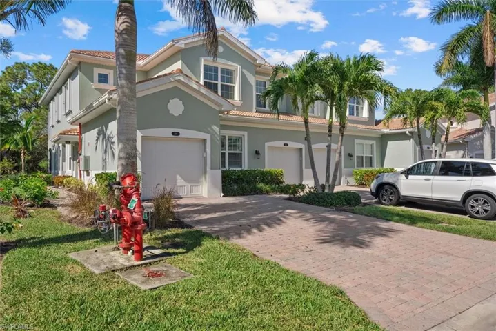 Stucco exterior with a tile roof, integrated garage, and a paver driveway