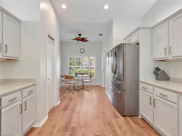 Kitchen featuring freestanding refrigerator, light countertops, white cabinetry, a ceiling fan, and light wood-style flooring