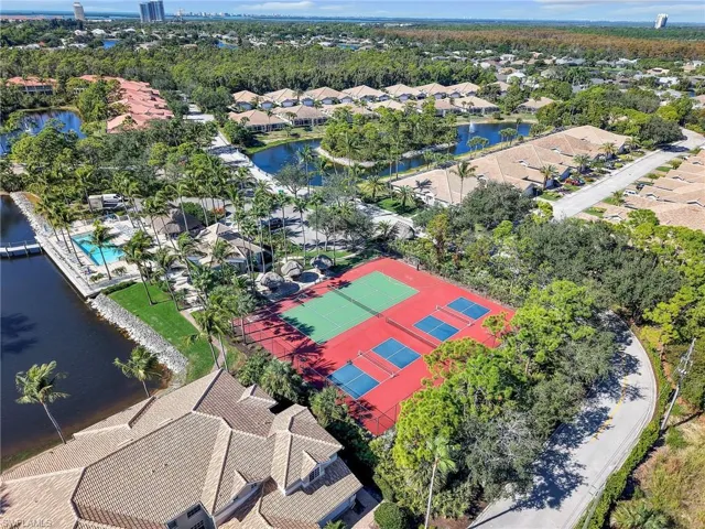 Aerial view of residential area featuring a nearby body of water and a tree filled landscape