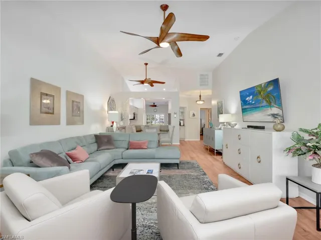 Living room featuring light wood-style floors, a ceiling fan, and high vaulted ceiling